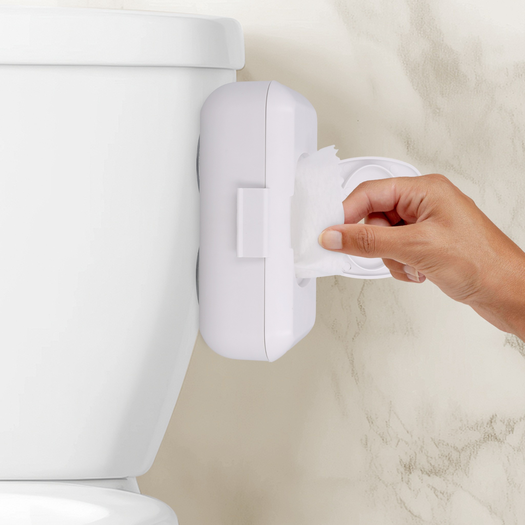 Loo dispenser mounted on a toilet tank with a wipe being pulled